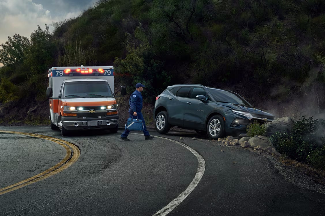 A vehicle crashed on the side of the road with an ambulance next to it.