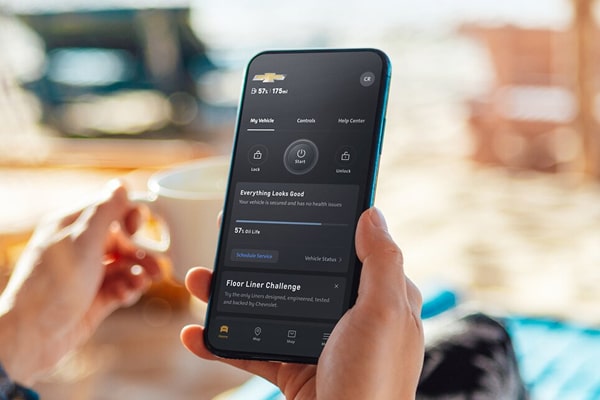 A woman's hand holding a smartphone showcasing the OnStar app