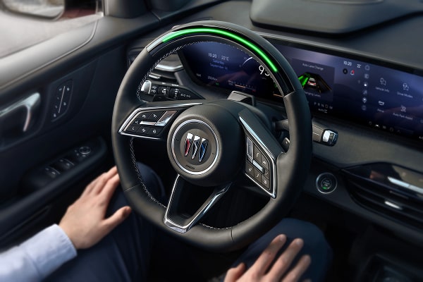 An aerial view of a driver using hands-free driving with the green light on the steering wheel lit up.