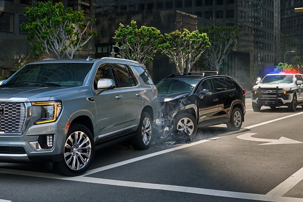 Two SUVS in a rear ending accident and a police vehicle behind them with its lights on.