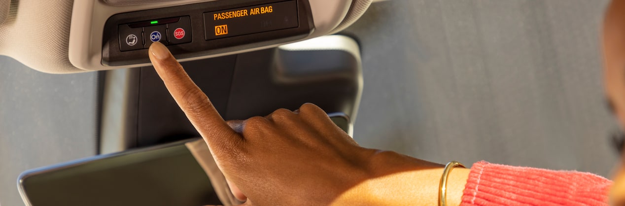 Close Up of a Driver Wearing Red Pressing the OnStar Button