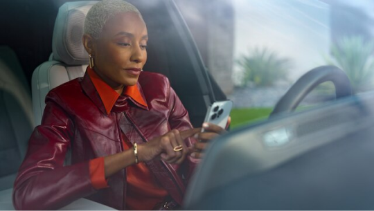 A woman sitting in her car using her smartphone 