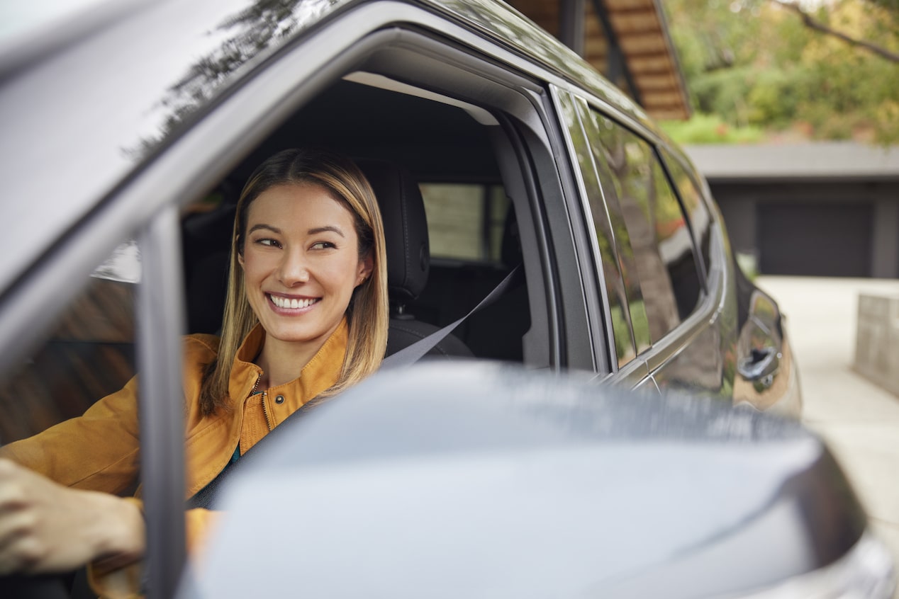 Female Driver in Yellow Smiling Out of the Open Window