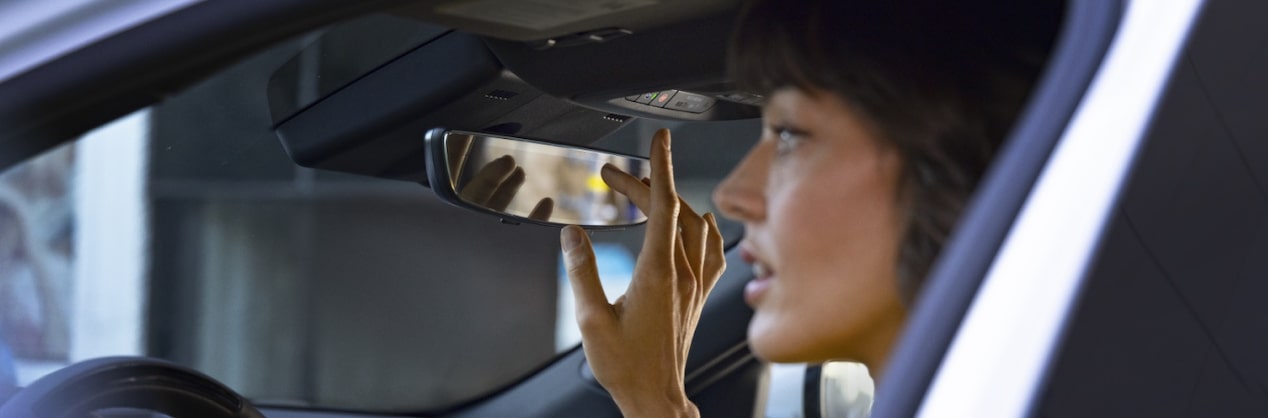 Woman Sitting in Vehicle Adjusting Rear View Mirror 