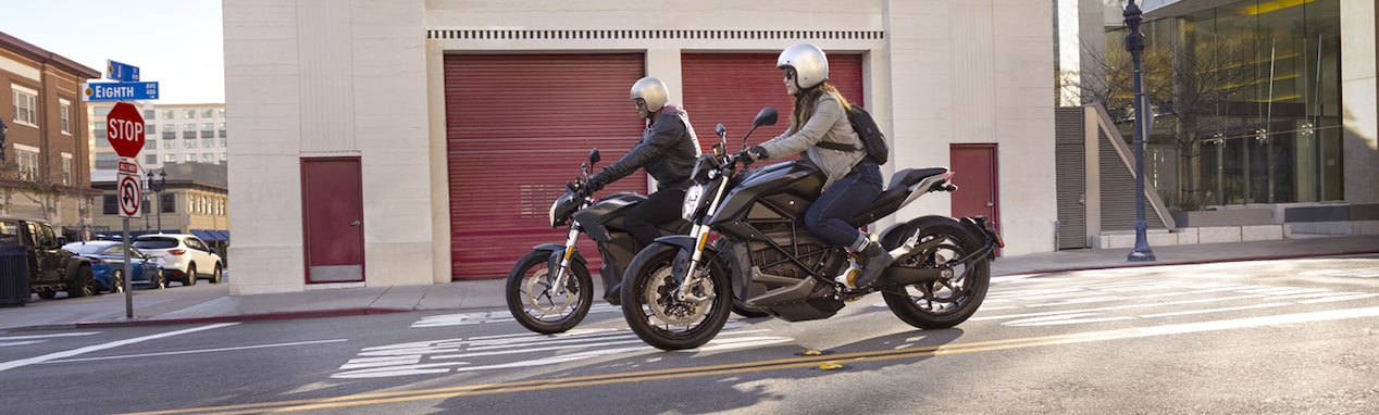 Two motorcycles driving down a city street