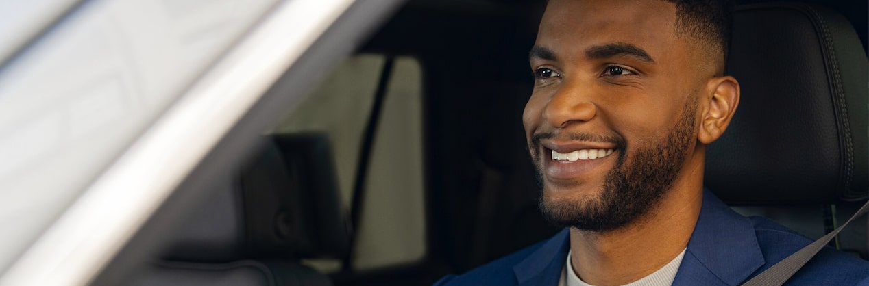 A man in the driver's side seat of a vehicle is smiling as he is looking forward