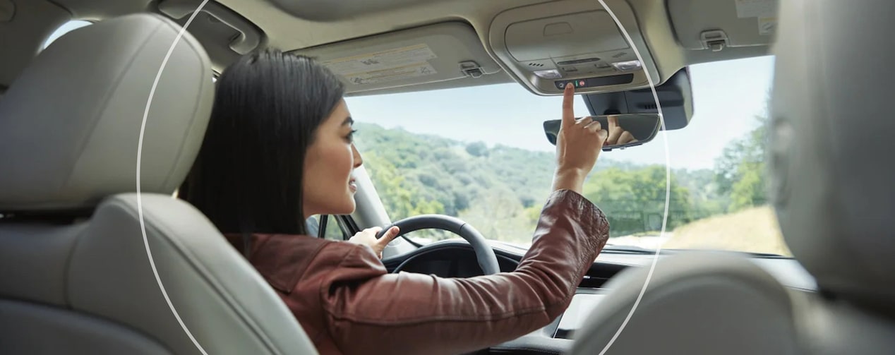 Backseat View of Woman Driver Pressing OnStar Button