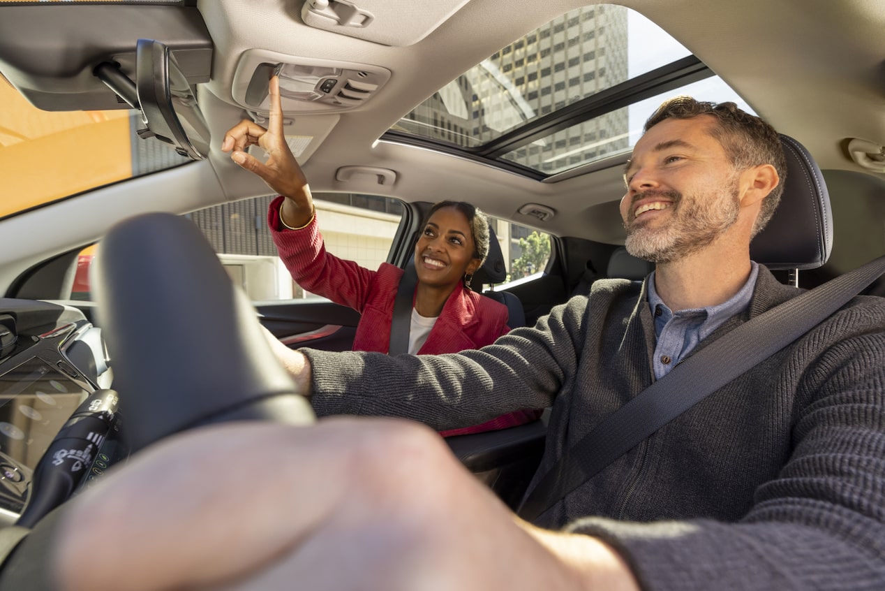 Woman Presses the OnStar Button While the Man Drives