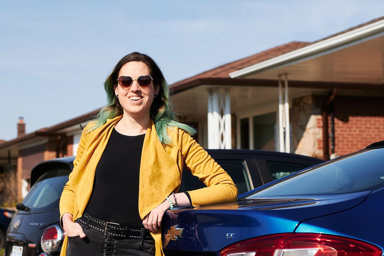 Woman Smiling While Leaning on the Back of her Vehicle