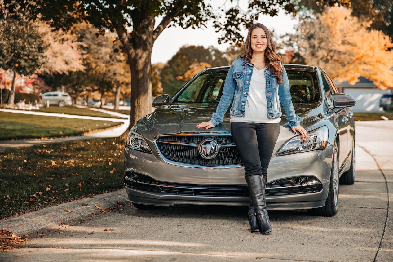 Women Smiling While Leaning on Hood of Buick Vehicle