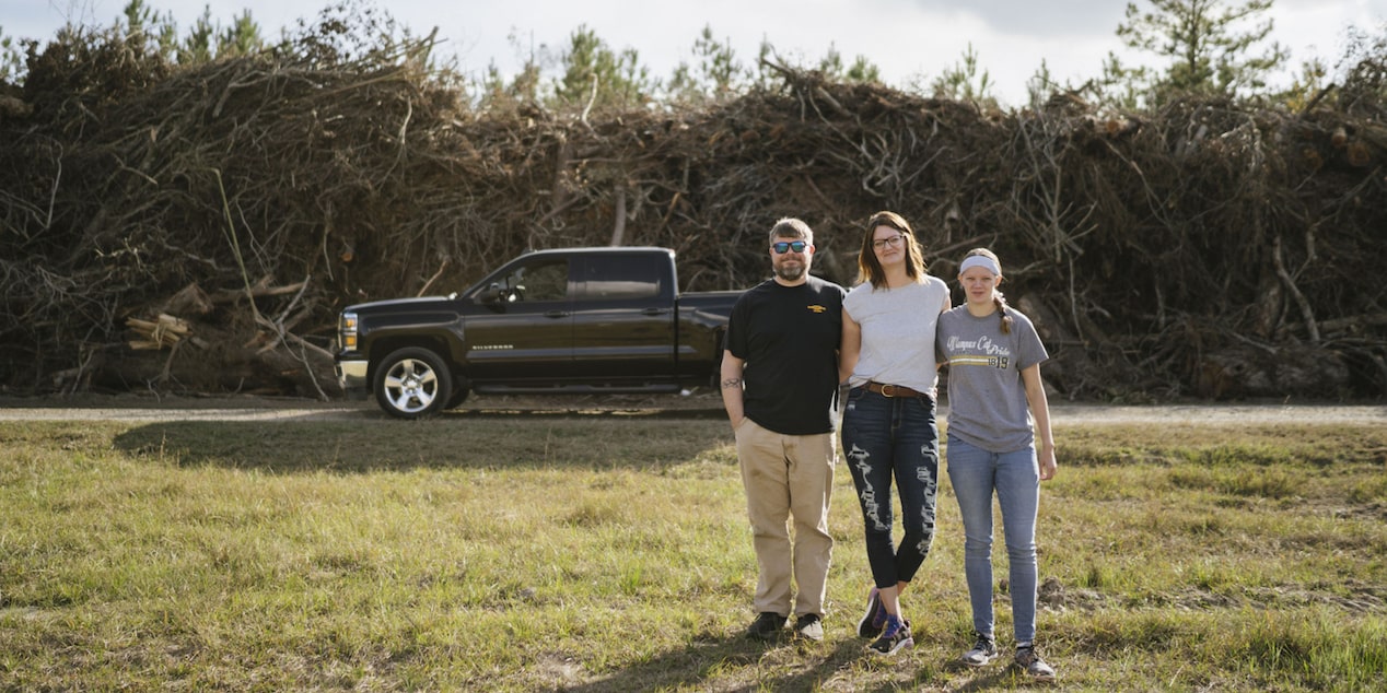 Family of 3 Standing Side by Side in Front of Their GM Vehicle