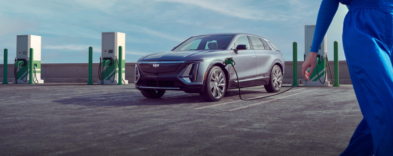 A Cadillac LYRIQ is plugged into a charger on the top floor of a parking garage.