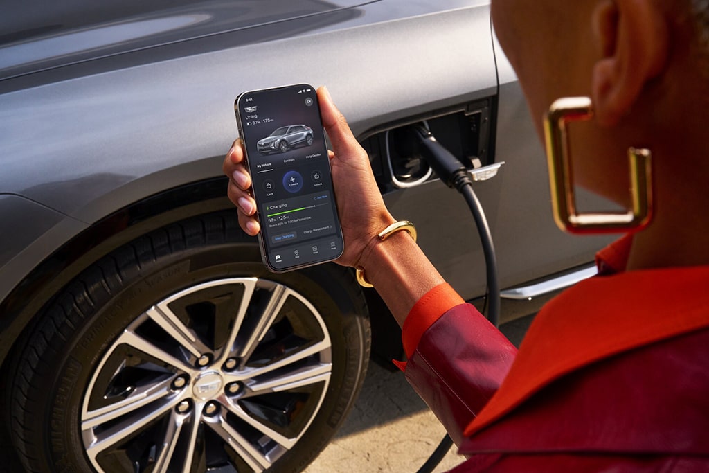 A person uses the myCadillac app on their phone while standing next to their vehicle.