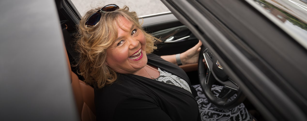 OnStar member Barbara Wrench smiling at the camera through her Cadillac sunroof