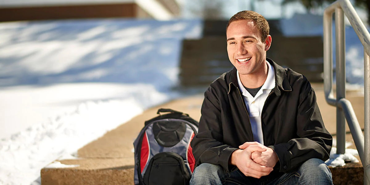 College Student Sitting on Steps with Backpack