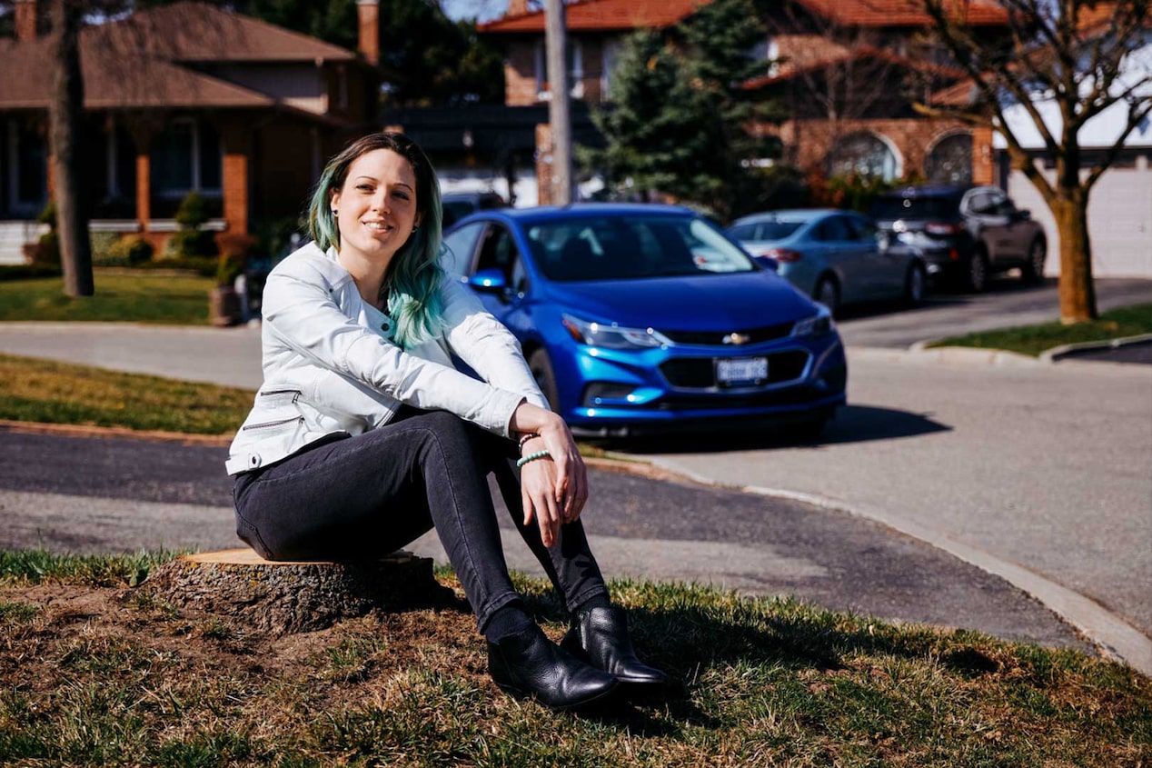 Woman Sitting Smiling with her GM Car in the Background