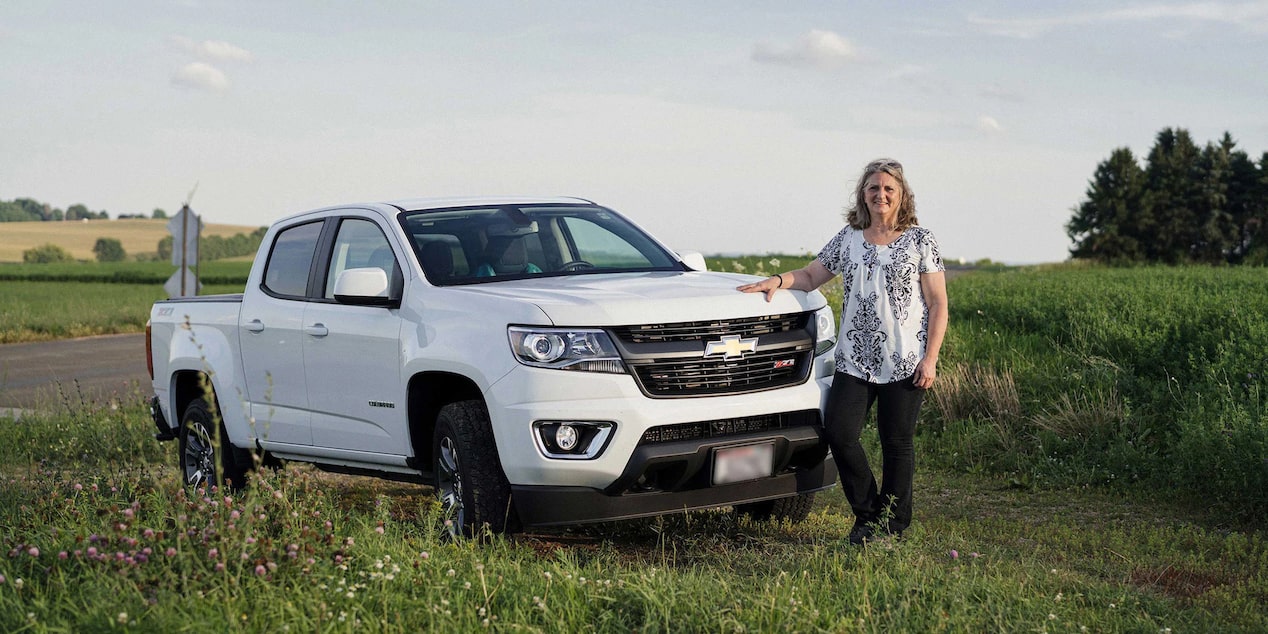 Woman Standing Smiling Near the Front of Her Chevy Truck