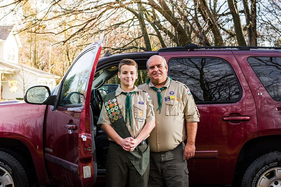 Father and Son Boy Scout Standing in Front of GM SUV