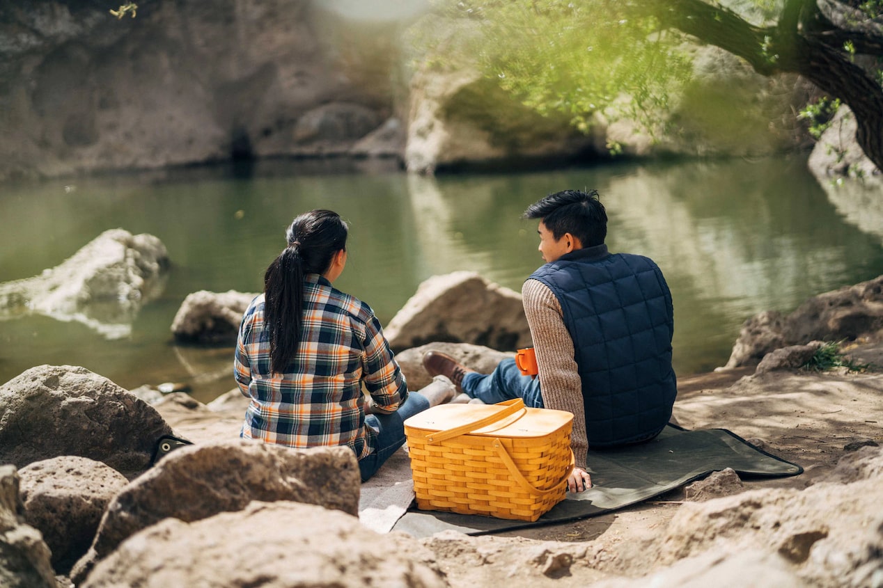 Couple Sitting Next to River with a Picnic Basket