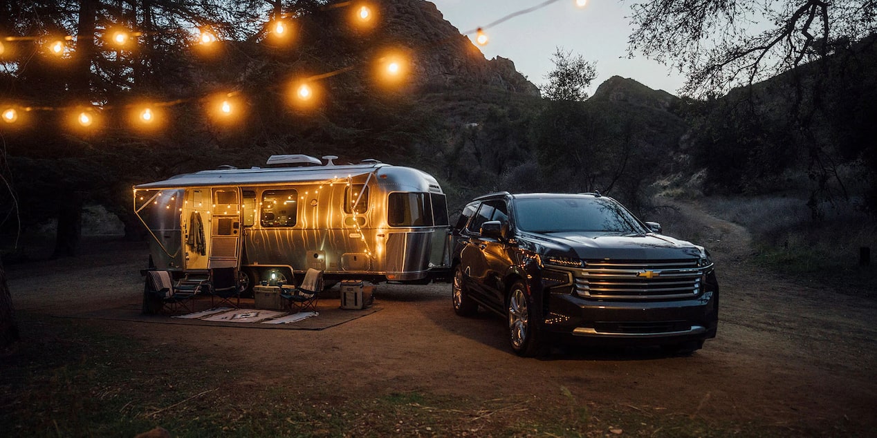 Chevy Vehicle Parked in Woods at Night with Camper Attached