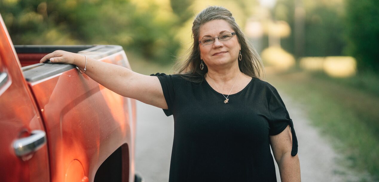 Woman Smiling With Her Arm Laid On the Bed of a GM Truck