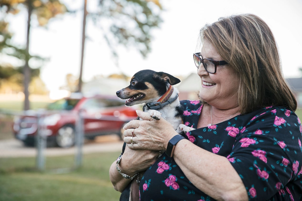 Woman Holding Small Dog With GM Vehicle in the Background