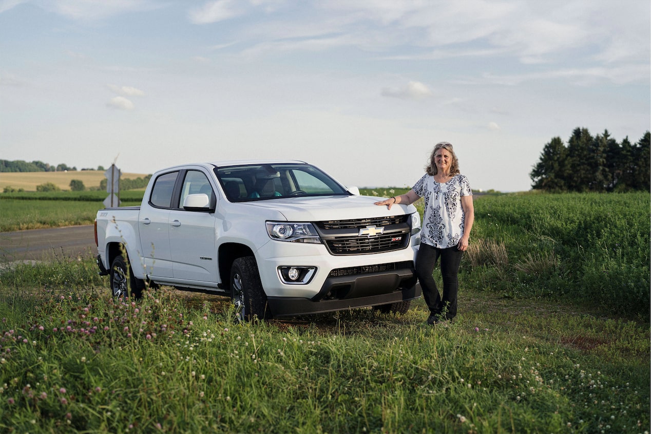 Woman Standing Next to Her Chevy Truck in a Field 