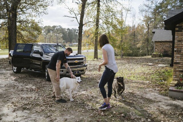 Couple in Driveway Playing with Their Dogs 