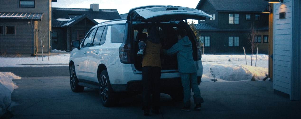 Couple loading skiing gear into the back of their GM vehicle