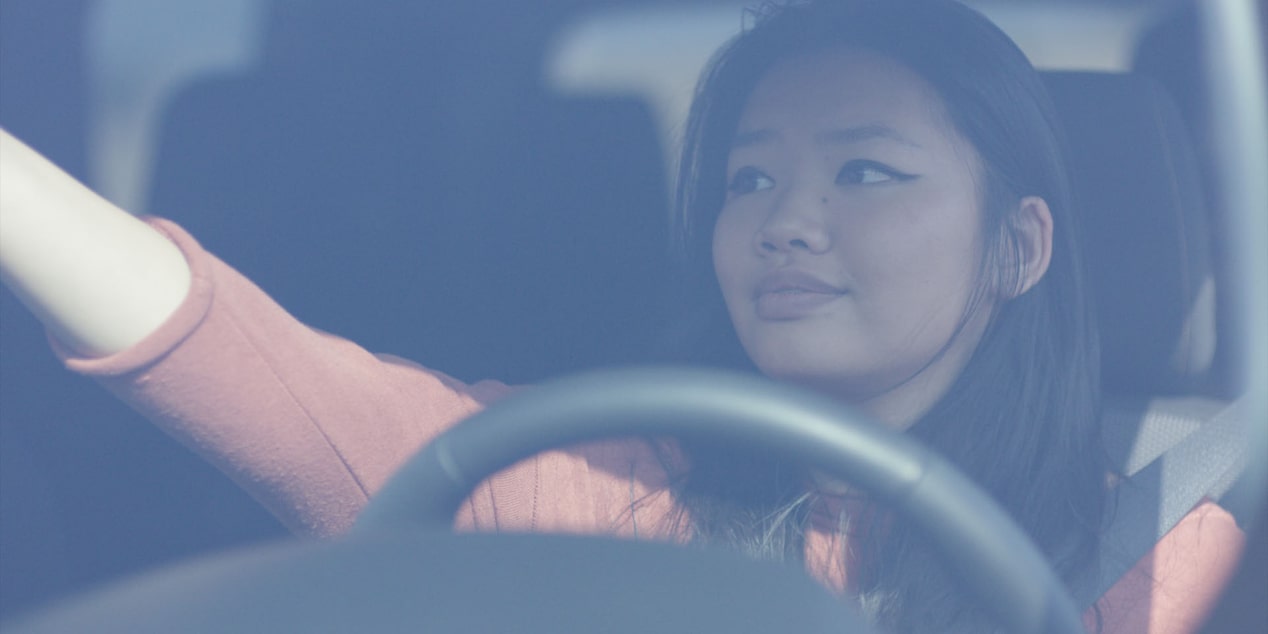 Women Sitting in Drivers Seat Adjusting Rear View Mirror