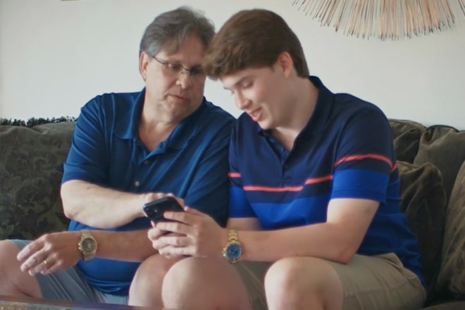 Father and Son Sitting Down Looking at a Smartphone