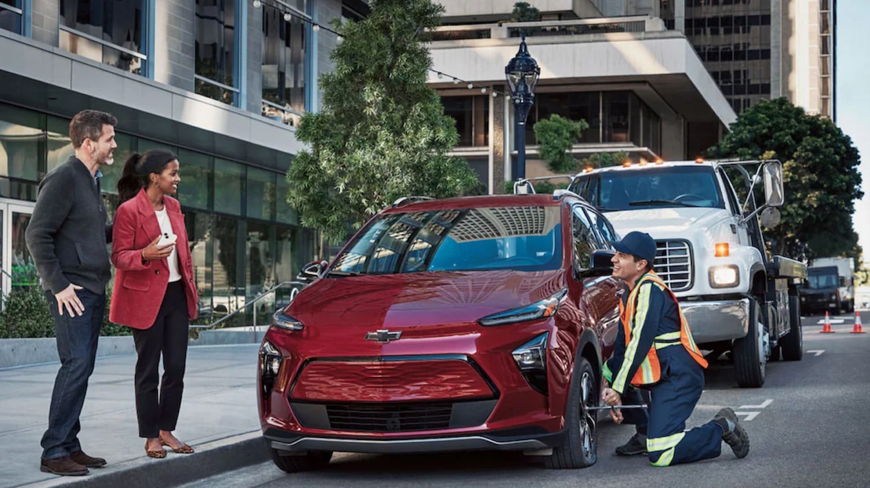 A Couple Standing Next to Their Chevy EV Getting Help From Roadside Assistance