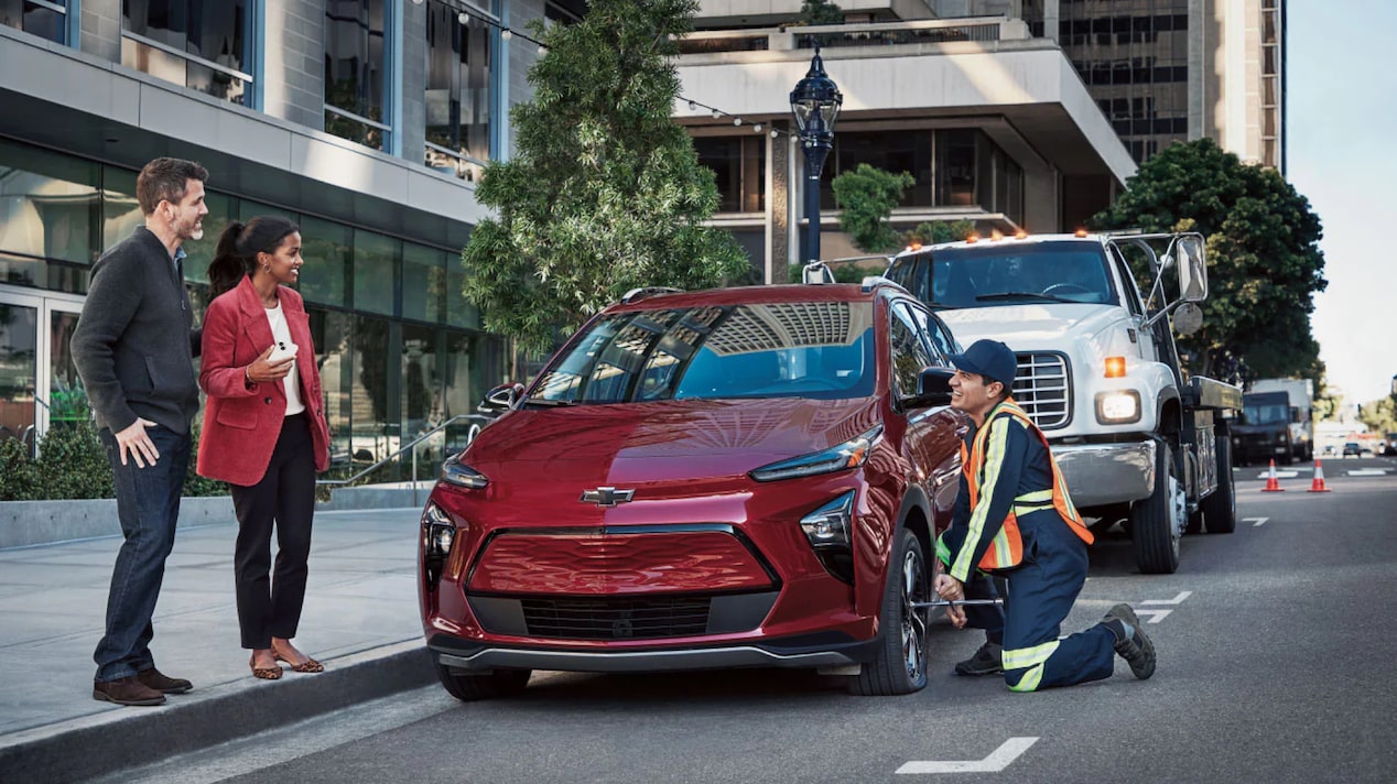 A Couple Standing Next to Their Chevy EV Getting Help From Roadside Assistance