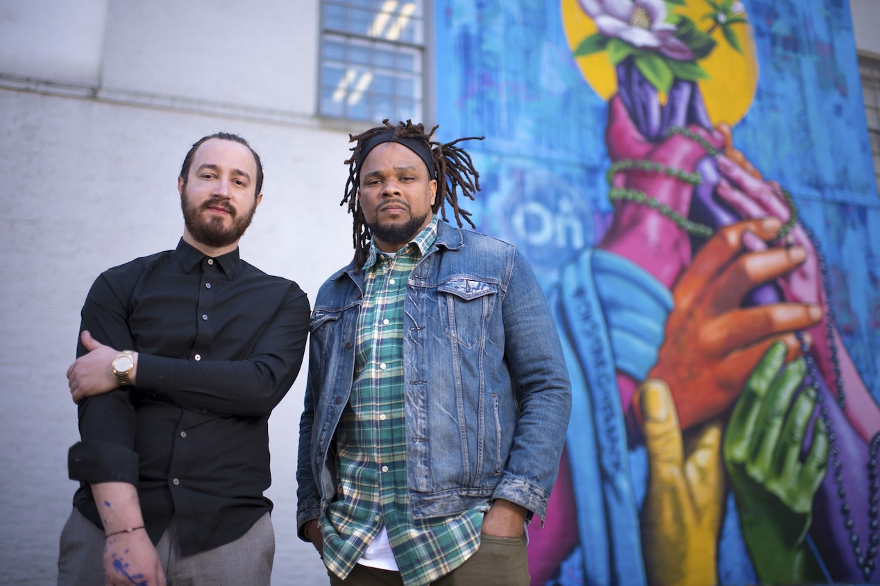 Two Men Standing in Front of Mural