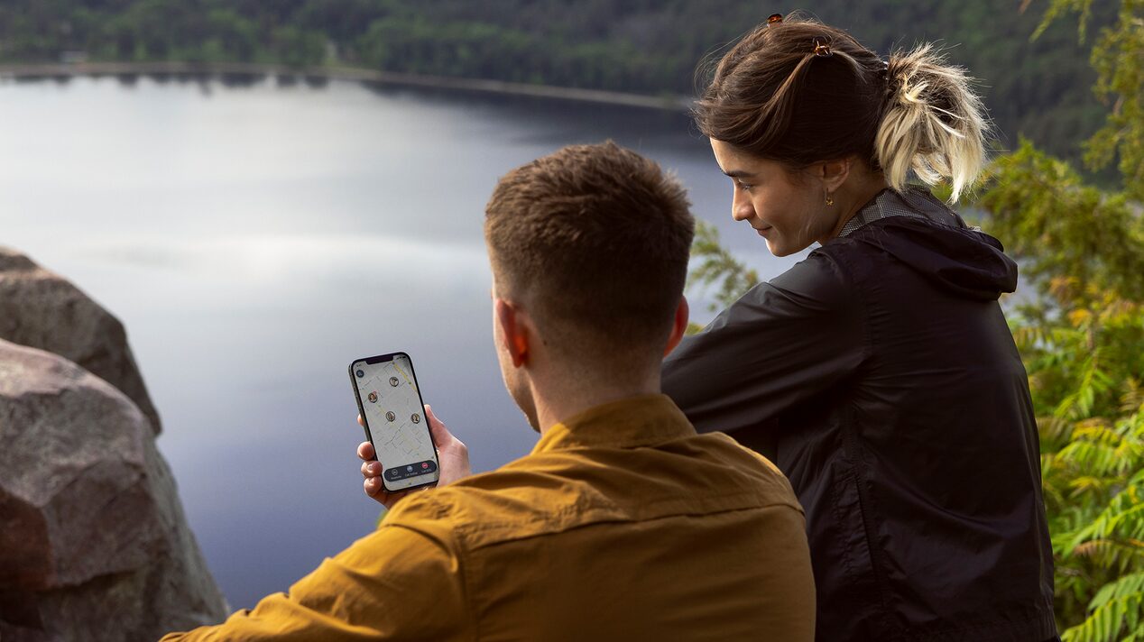 Couple Looks at Phone While Overlooking a Lake