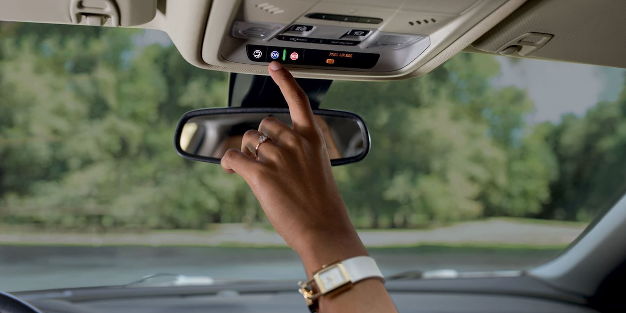 Close up of Driver Pressing the OnStar Button on a Tree Lined Road