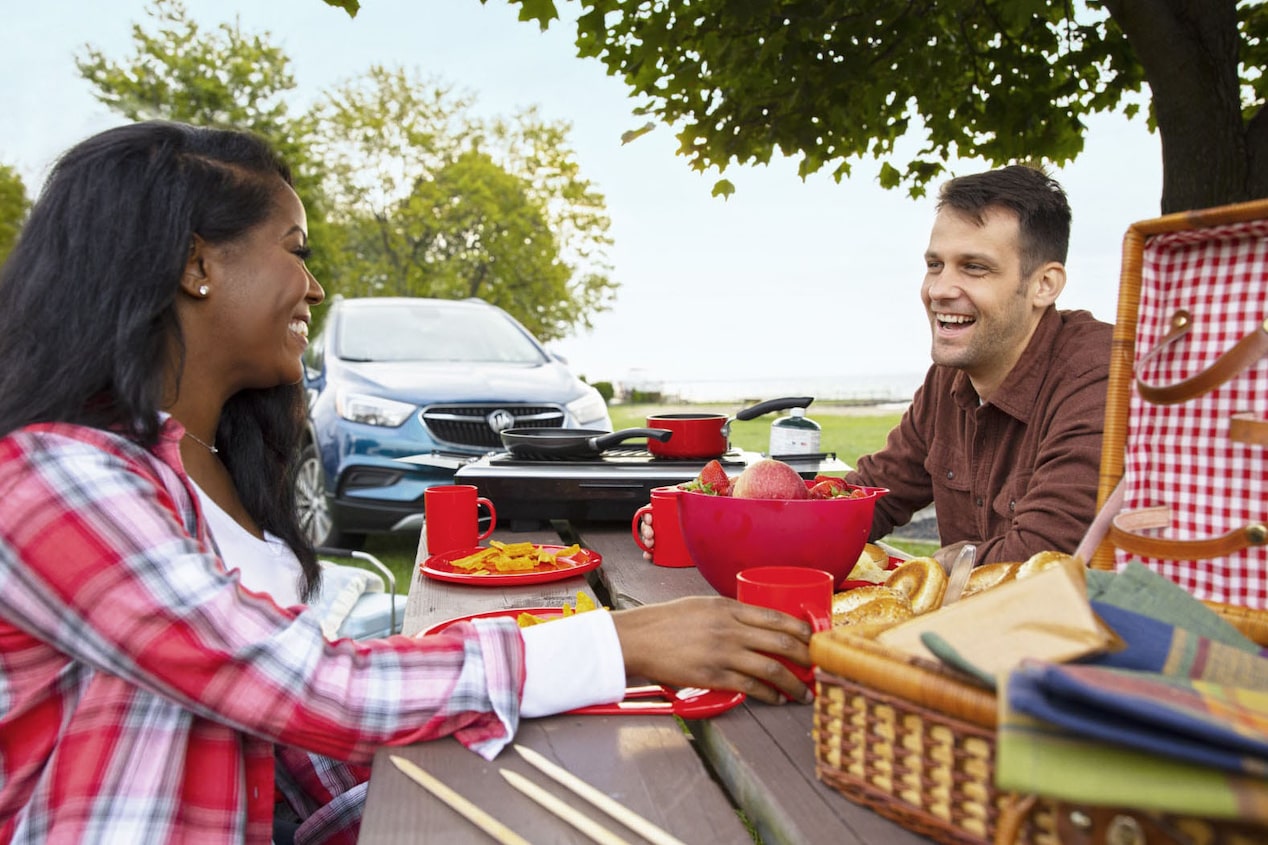 Couple Enjoying Lunch on a Picnic Table on a Road Trip