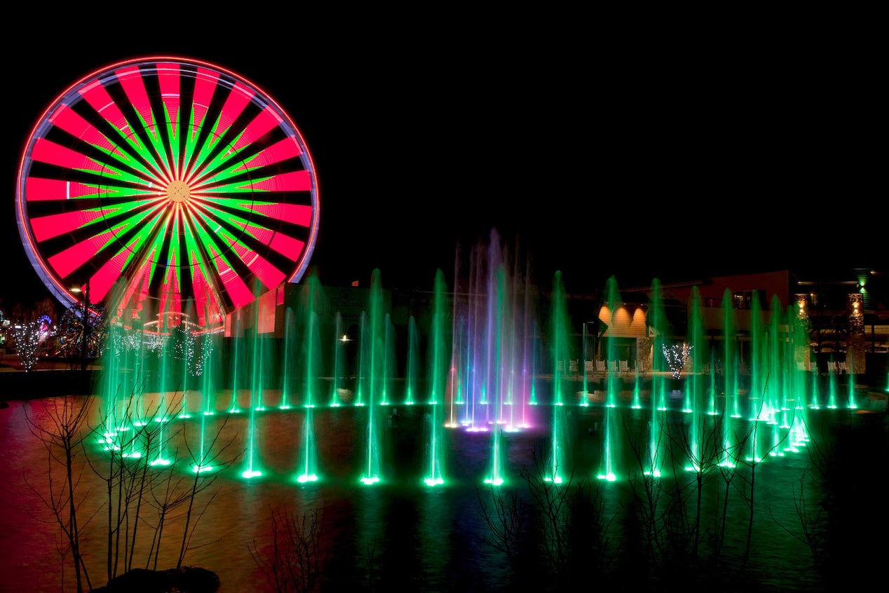 Red and Green Lit Up Ferris Wheel and Fountain