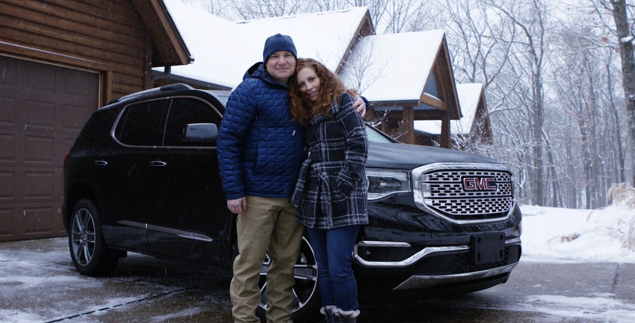 Couple Standing Infront of Vehicle with Snow on the Ground